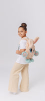 Child wearing adorable plush toy backpack with bunny ears sensory 3D paws and blue accents, perfect for kids, shown on a white background.