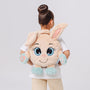 Child wearing a plush bunny backpack ,with sensory 3D paws,against a plain background