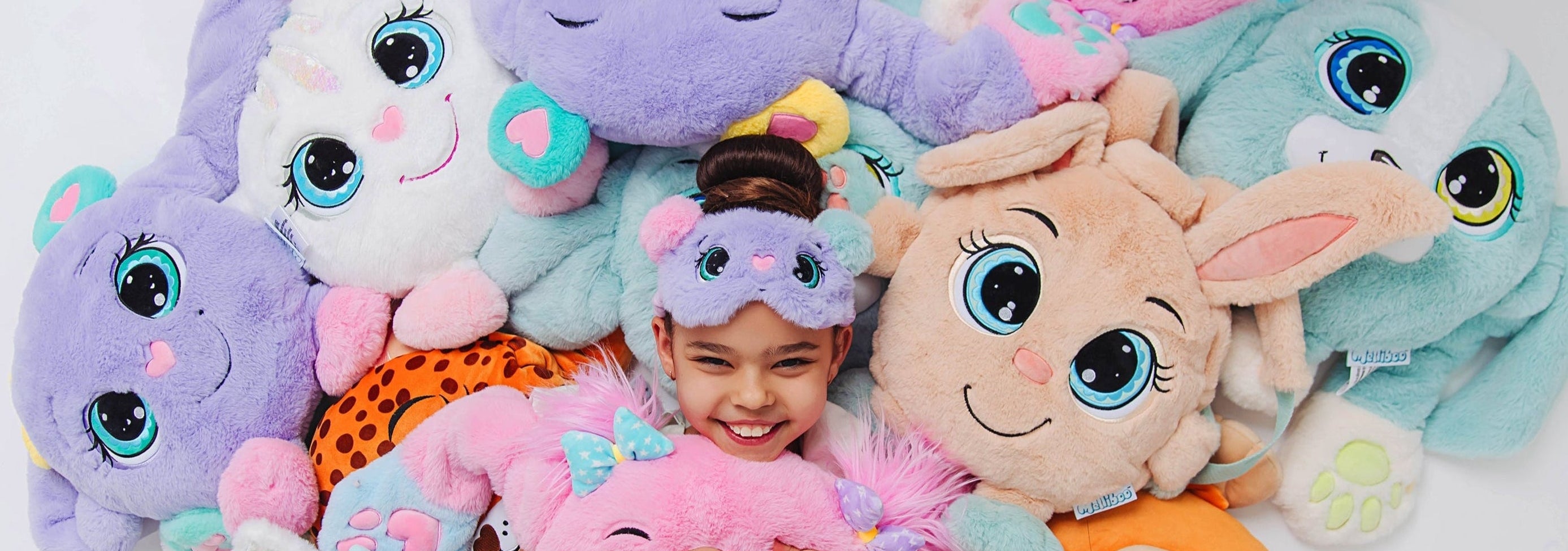 Girl surrounded by colorful weighted plush toys with large eyes on a white background