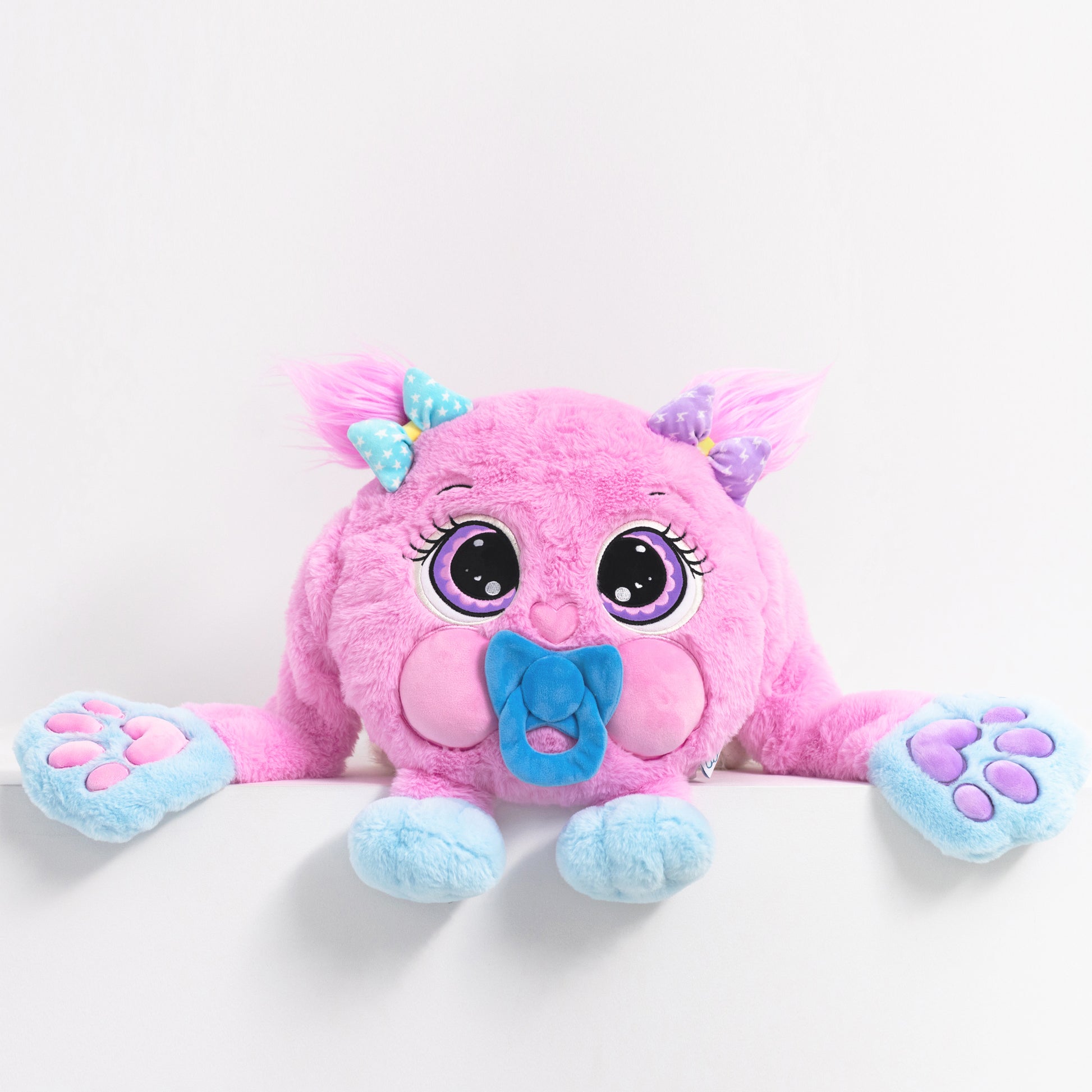 Pink plush toy with purple big eyes on a white background. They toy is weighted and helps with anxiety and stress. 