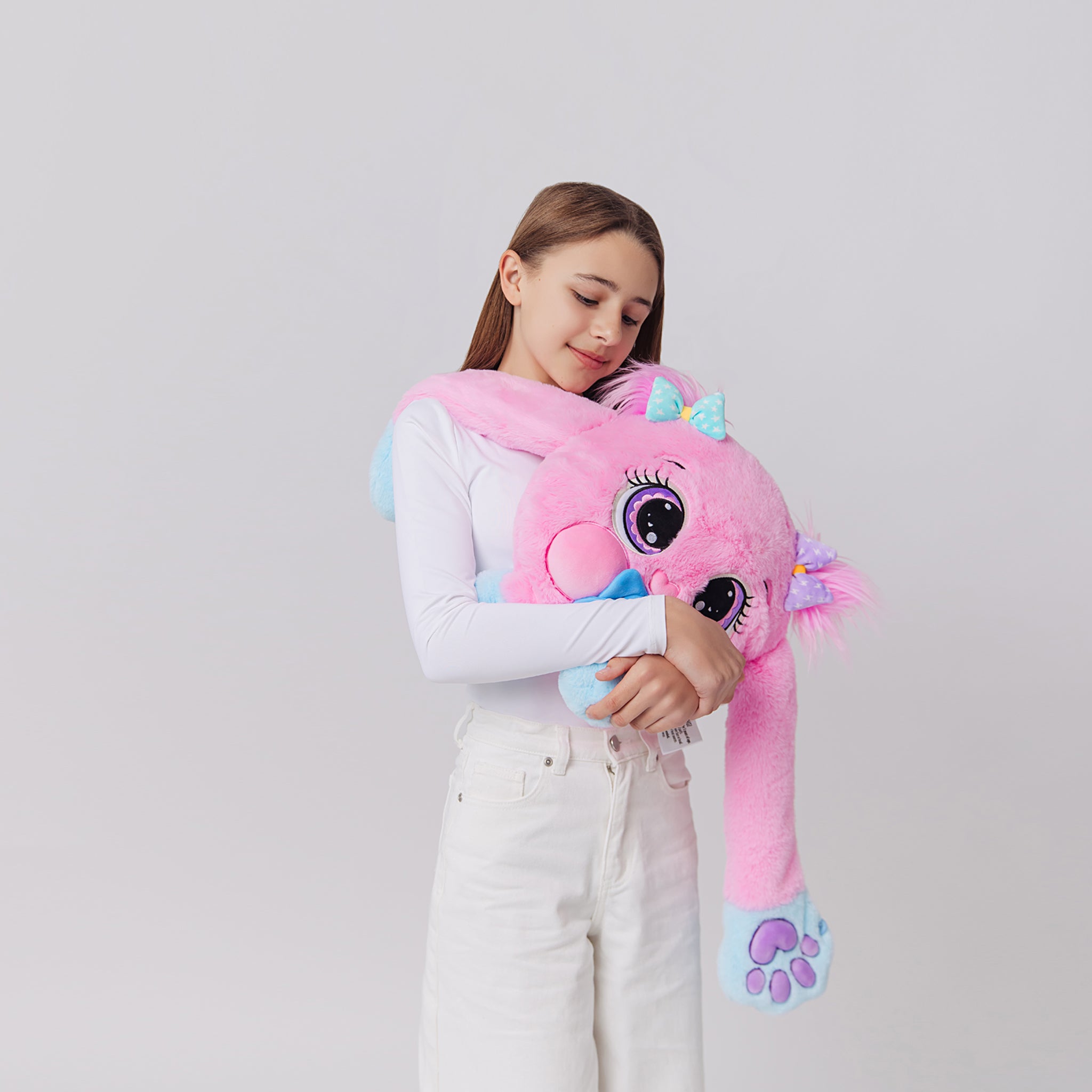 Girl holding pink plush weighted toy featuring 3D sensory cheeks, paws, and nose, with pink paws, blue accents, and large expressive eyes. This soft, cuddly sensory plush is perfect for relaxation, stress relief, and comfort, displayed on a clean white background.