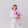 Girl holding pink plush weighted toy featuring 3D sensory cheeks, paws, and nose, with pink paws, blue accents, and large expressive eyes. This soft, cuddly sensory plush is perfect for relaxation, stress relief, and comfort, displayed on a clean white background.