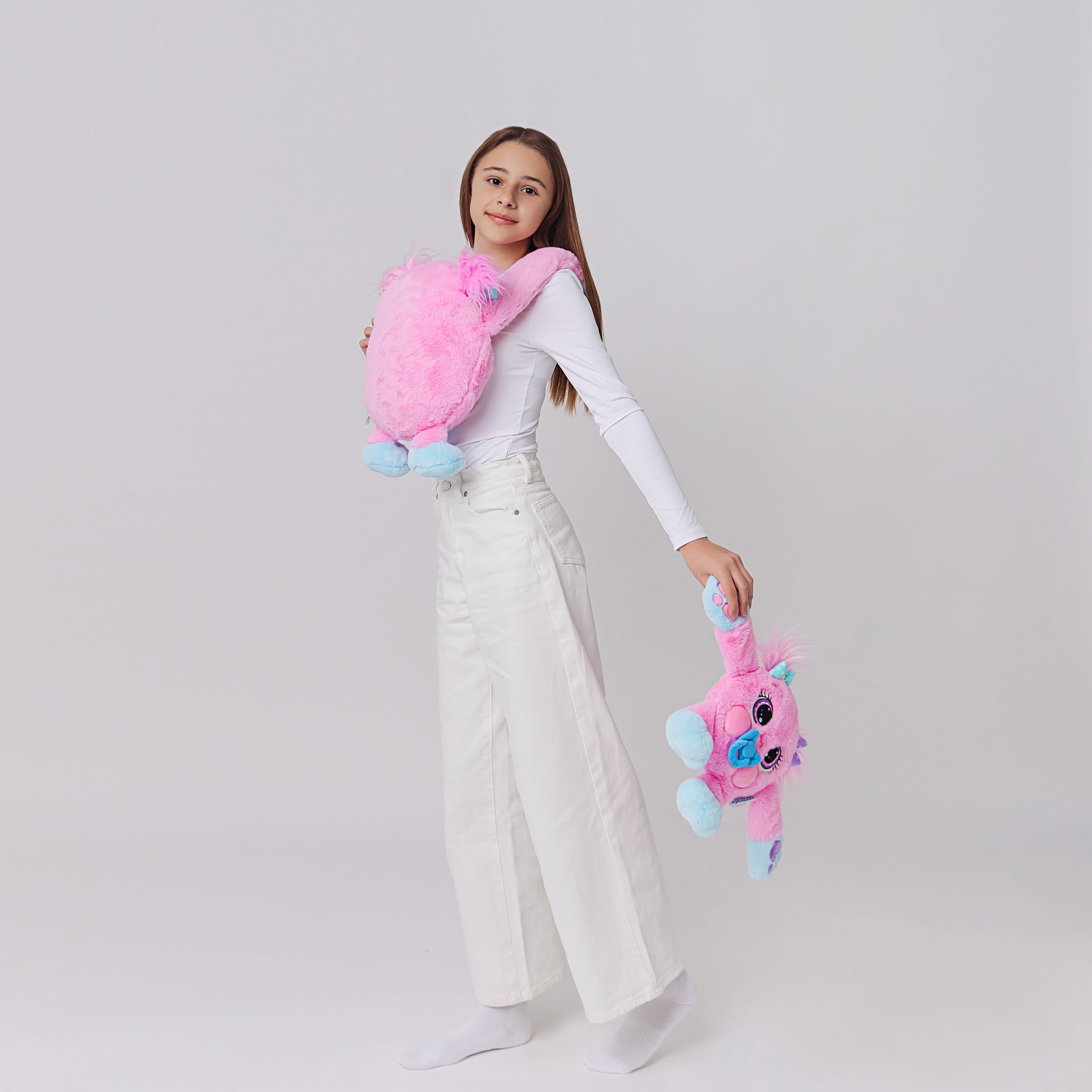 Person holding and hugging a pink weighted toy featuring 3D sensory cheeks, paws, and nose, with large eyes set against a white background.
