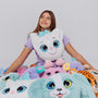 Girl holding a large weighted plush toy with a white face and blue accents, surrounded by similar plush toys on a plain background.