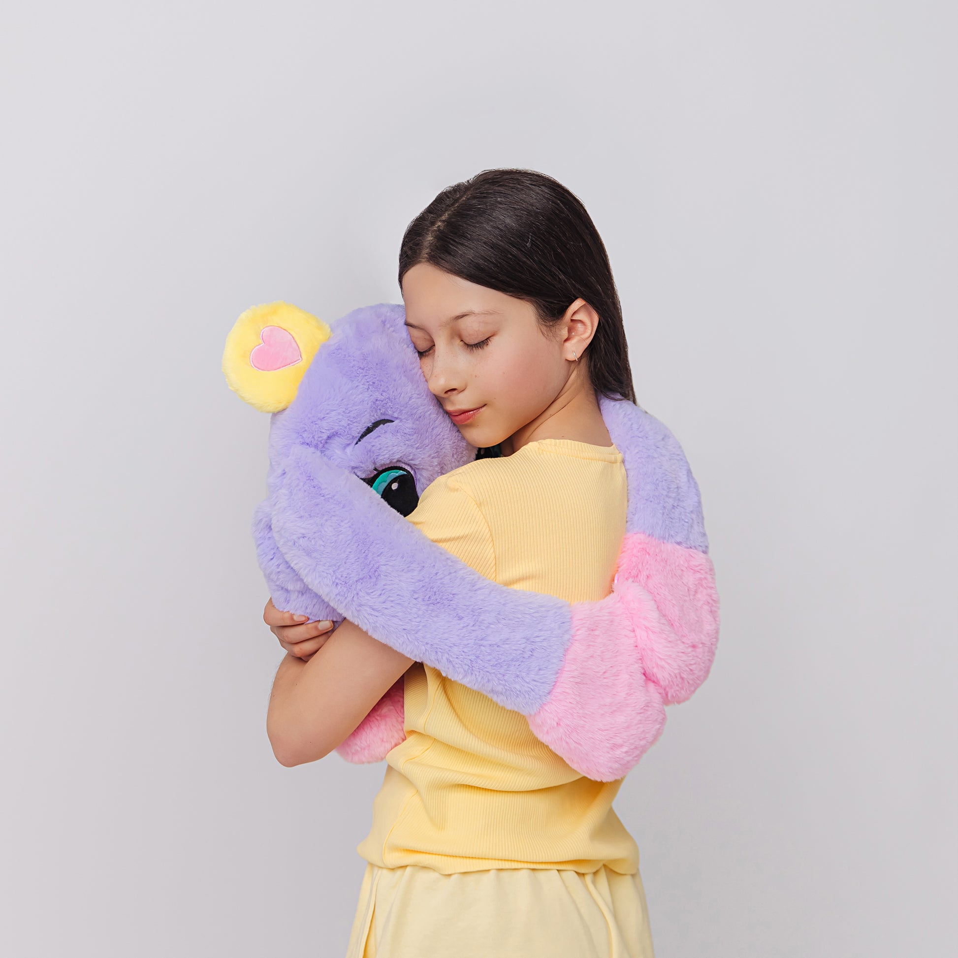 Girls hugging a purple plush weighted toy featuring 3D sensory cheeks, paws, and nose, with pink paws, blue accents, and large expressive eyes. This soft, cuddly sensory plush is perfect for relaxation, stress relief, and comfort, shown on a clean white background.