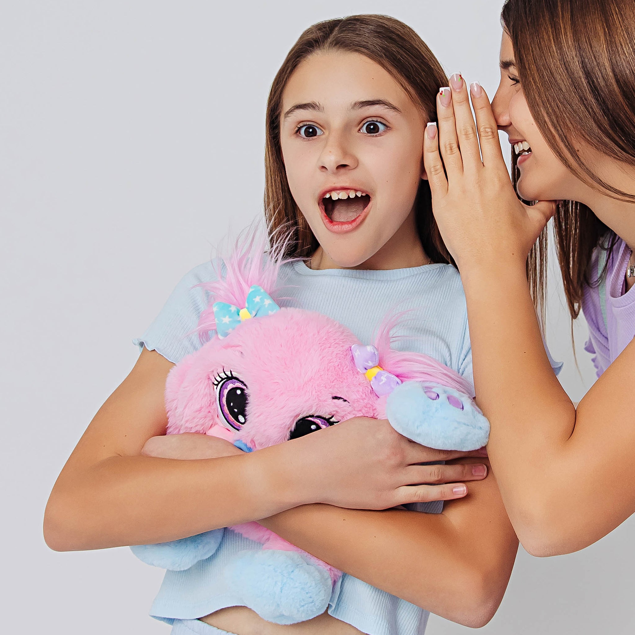 Girl holding a pink weighted toy featuring 3D sensory cheeks, paws, and nose, with large eyes plush toy,with another person whispering into her ear against a light gray background