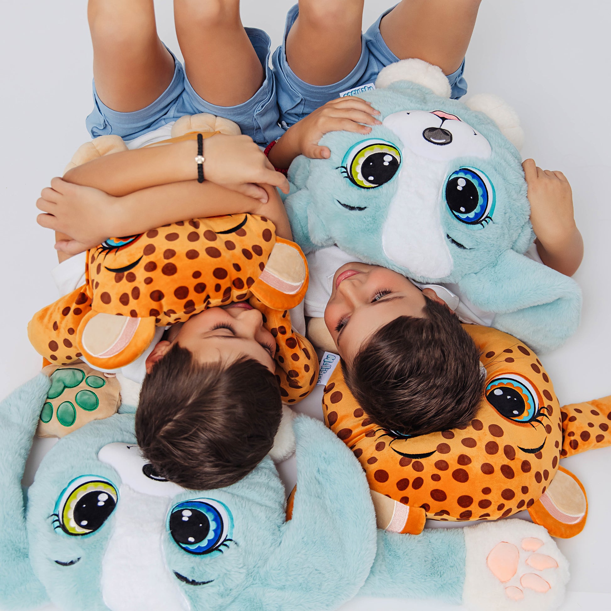 Two children lying on a white surface with a  weighted Plush Leopard and  Blue Puppy.These ultra-soft, cuddly sensory plushies provide comfort, relaxation, and stress relief, beautifully displayed on a clean white background.